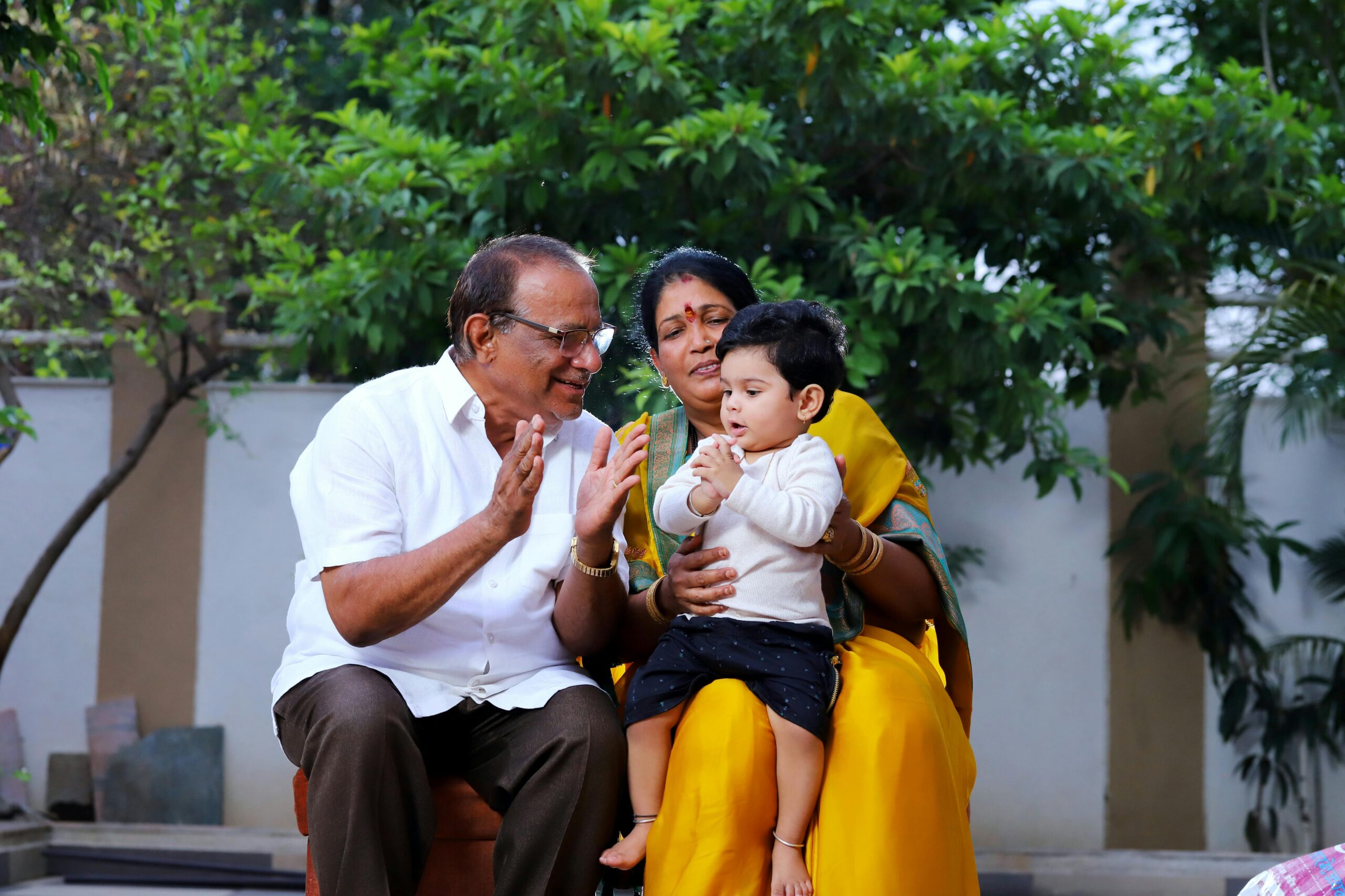 A joyful Indian family scene with grandparents and a child enjoying time outdoors in Malegaon, India.