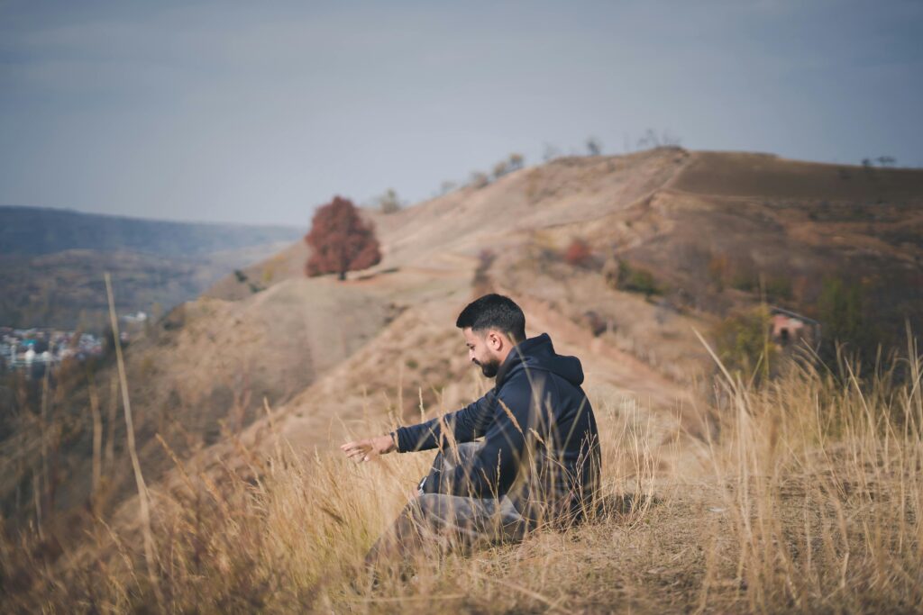 A man in Srinagar enjoys the serene autumn landscape while sitting on a hill.