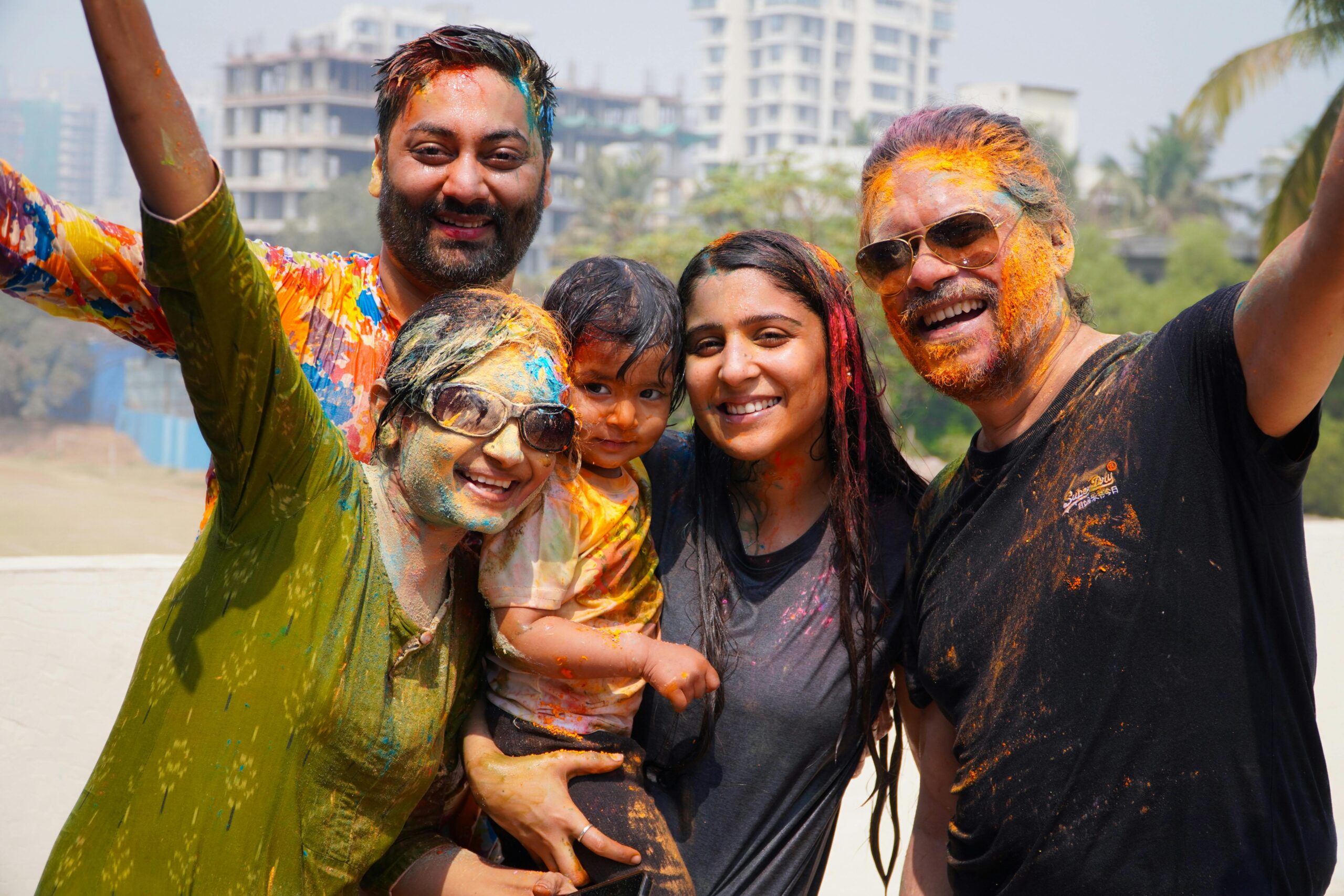 Cheerful family enjoying Holi festival with vibrant colors outdoors.