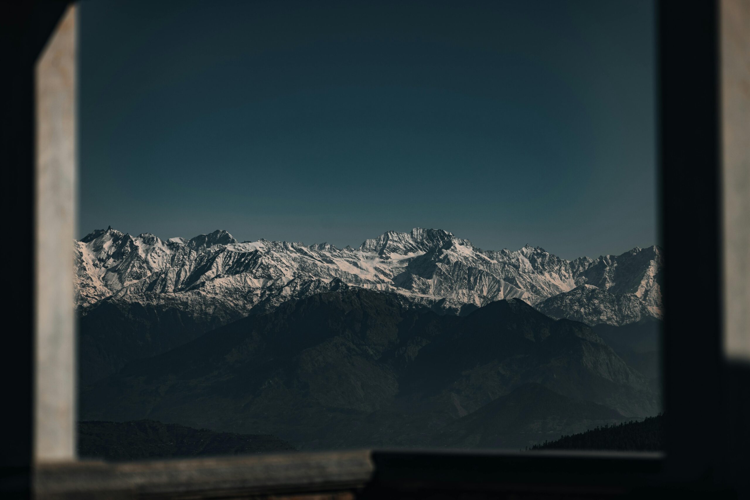 Snow-covered peaks of the Himalayan mountains beautifully framed by a window view.