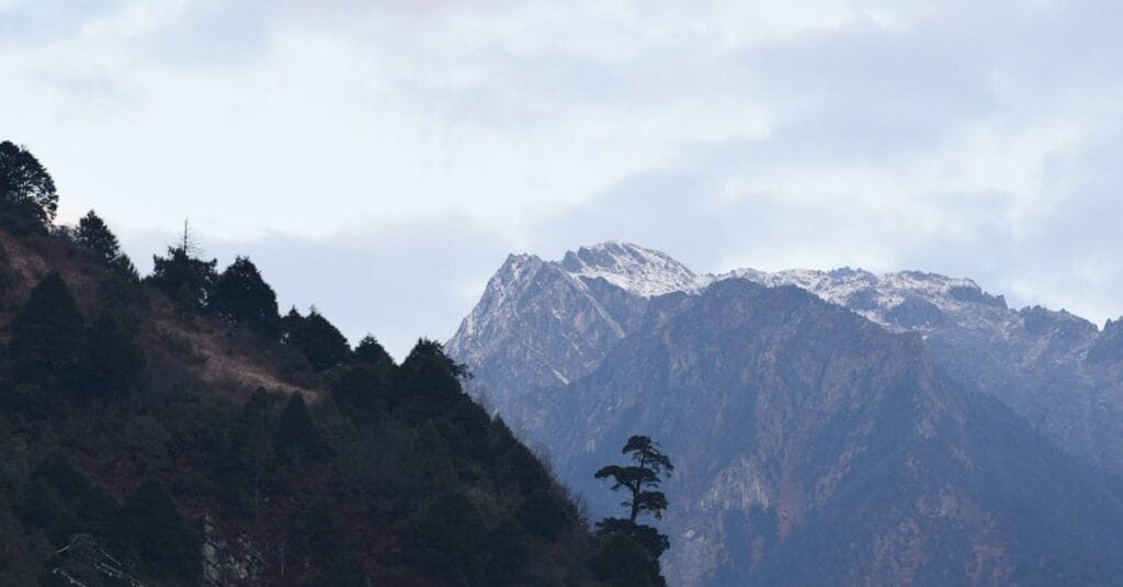 Breathtaking view of the Himalayas in Lachen, India with lush greenery and cloudy skies.