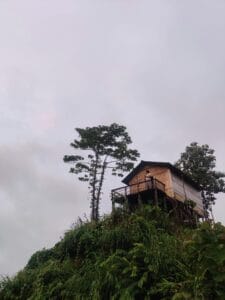 Scenic view of a hilltop cabin surrounded by lush greenery in Bandarban, Bangladesh at dawn.