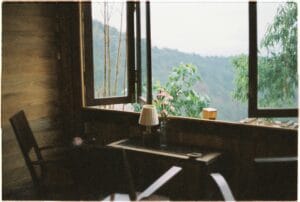 A cozy interior featuring a wooden table, flowers, and a scenic window view.